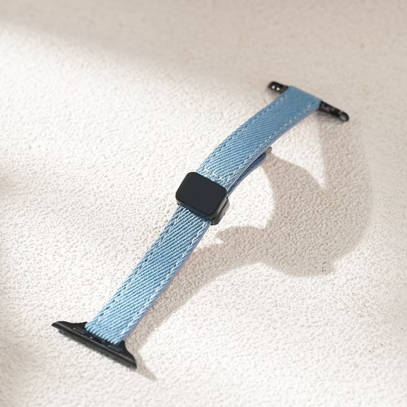 Blue woven watch strap with black clasp on a textured surface