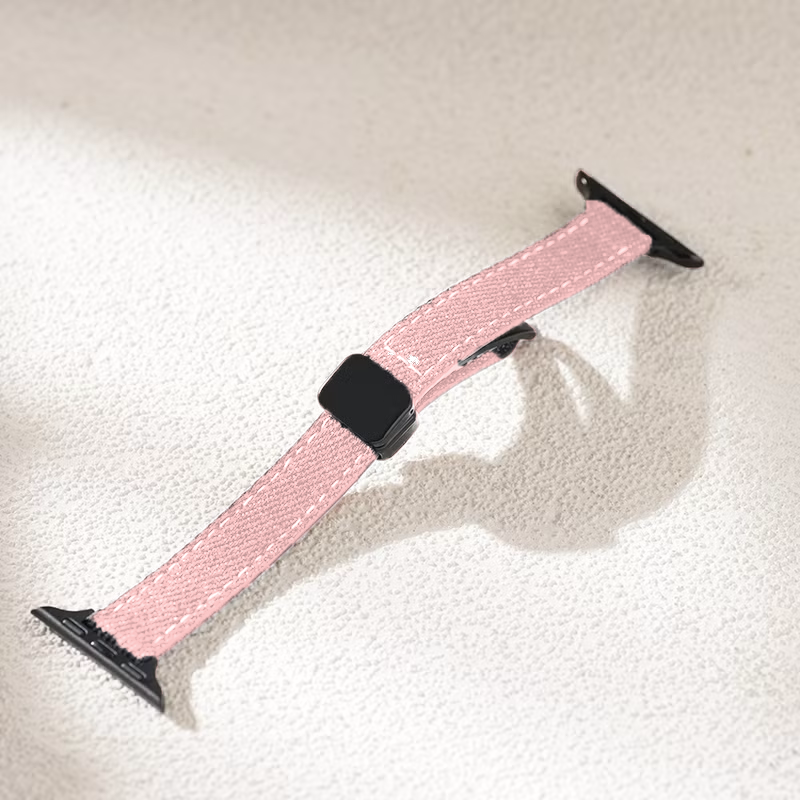Pink watch strap with black hardware on a light gray background